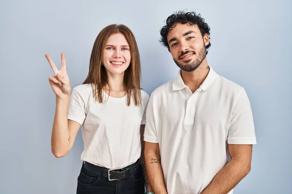 自信と幸せな笑顔ながら カジュアルな服を身に着けている若いカップルが一緒に立って指の数2を示すと指摘 — ストック写真