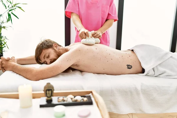 Young Redhead Man Having Back Massage Using Thai Bags Beauty — Stockfoto