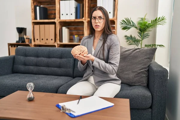 Mulher Hispânica Trabalhando Escritório Terapia Segurando Cérebro Cético Nervoso Franzindo — Fotografia de Stock