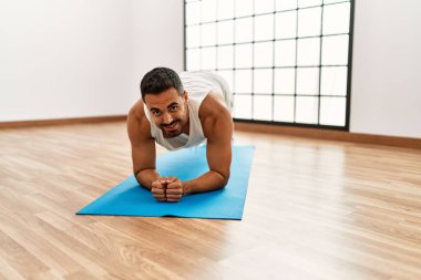 Genç İspanyol adam gülümsüyor spor merkezinde kendine güvenen karın kasları egzersizi yapıyor.