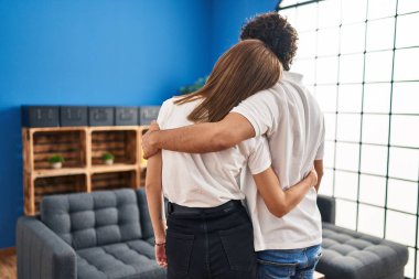 Man and woman on back view hugging each other at home
