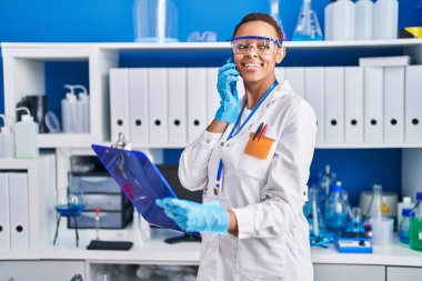 Afrika kökenli Amerikalı kadın bilim adamı laboratuvarda akıllı telefon okuyarak konuşuyor.