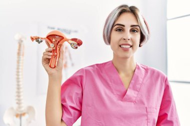 Dölyatağı tüpü anatomik modeli taşıyan beyaz bir jinekolog klinikte duruyor..