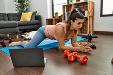 Young woman having online stretching class at home