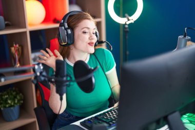 Genç kızıl saçlı kadın, gülümsüyor. Oyun odasında kendine güvenen bir video var.