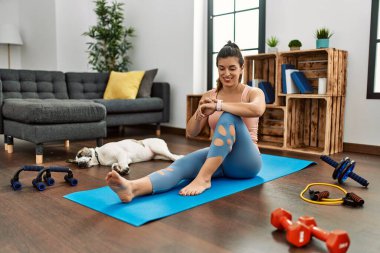 Evde kendine güvenen genç bir kadın kronometreye bakıyor.