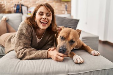 Yeni evimizde köpekle kanepede uzanmış kendinden emin gülümseyen beyaz bir kadın.