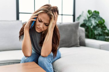 Young caucasian girl with unhappy expression talking on the smartphone at home.