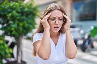 Sokakta baş ağrısı çeken genç sarışın kadın.