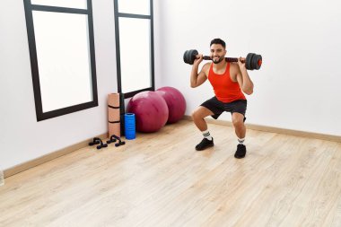Genç Arap adam gülümsüyor spor merkezinde halterleri olan kendine güvenen bir antrenman.