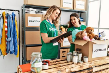İki gönüllü kadın, hayır kurumunda çalışmaktan mutlu gülümsüyor..
