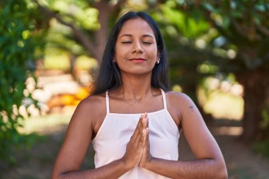 Genç ve güzel bir kadın parkta yoga egzersizi yapıyor.