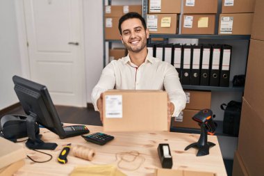 Sakallı, küçük bir iş yerinde çalışan, yüzünde mutlu ve havalı bir gülümsemeyle gülümseyen genç bir İspanyol. diş gösterme. 