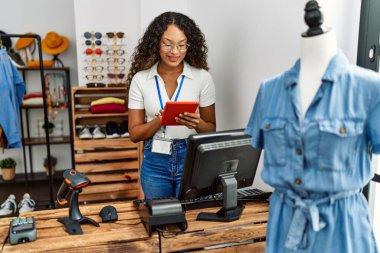 Genç Latin esnaf, giyim mağazasında çalışan dokunmatik ped kullanıyor..