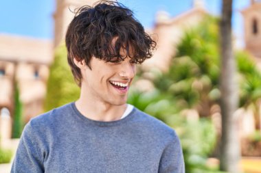 Parkta kendinden emin gülümseyen İspanyol genç adam.