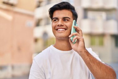 Genç İspanyol adam gülümsüyor. Kendine güveniyor. Sokakta akıllı telefondan konuşuyor.