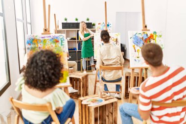 Resim stüdyosunda resim dersi alan bir grup insan..