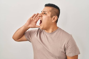 Latin kökenli genç bir adam beyaz arka planda durup el pençe divan durup bağırıyor. iletişim konsepti. 