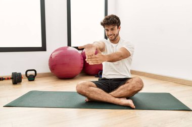 Genç İspanyol adam gülümsüyor spor merkezinde esniyor.