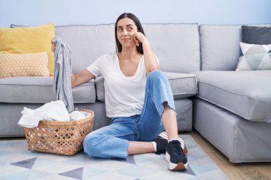 Genç esmer kadın evde çamaşır yıkıyor, gülümsüyor, yan tarafa bakıyor ve düşünüyor.. 