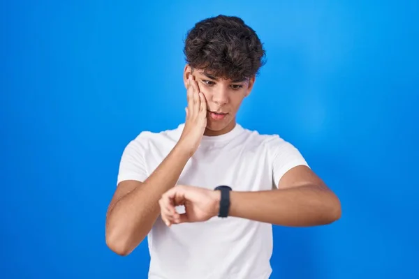 Latin Kökenli Genç Mavi Arka Planda Dikiliyor Saate Bakıyor Endişeli — Stok fotoğraf