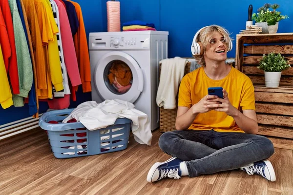 Çamaşır Odasında Çamaşır Makinesini Bekleyen Müzik Dinleyen Genç Sarışın Adam — Stok fotoğraf