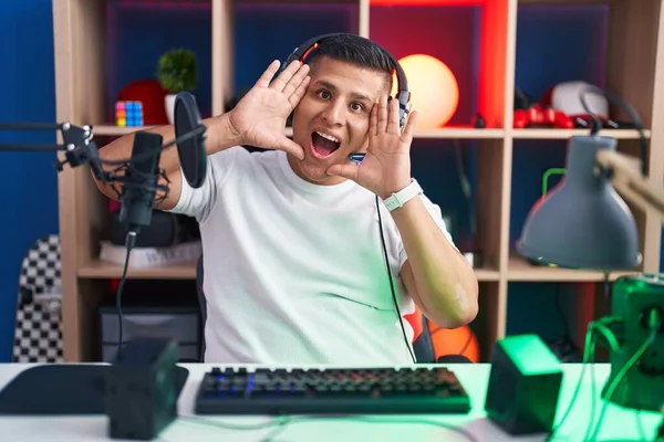 Молодой Латиноамериканец Играющий Видеоигры Веселый Улыбающийся Глядя Буу Поднятыми Руками — стоковое фото