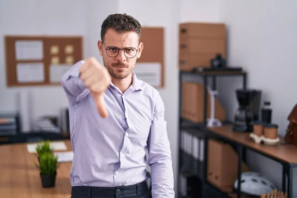 オフィスの若いヒスパニック系の男は 親指ダウンジェスチャーで拒絶と否定を示す不満と怒りを見ています 悪い表現 — ストック写真