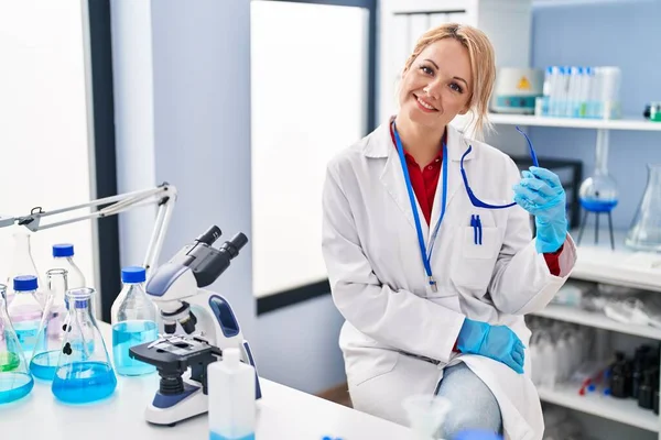 Young Blonde Woman Scientist Smiling Confident Holding Glasses Laboratory — Stock Photo, Image