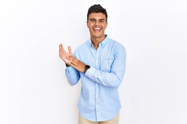 İspanyol iş gömleği giyen genç adam izole edilmiş arka planda ayakta alkışlıyor ve mutlu ve neşeli, gururlu elleri alkışlıyor. 