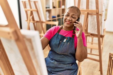 Kıdemli Afro-Amerikan kadın sanat stüdyosunda akıllı telefon çizimleriyle konuşuyor.