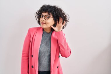 Kıvırcık saçlı İspanyol kadın, izole edilmiş arka planda dikiliyor. Kulağı kulağında, dedikoduları ve dedikoduları dinliyor. Sağırlık kavramı. 