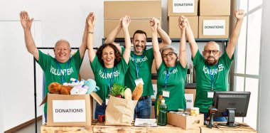 Yardım merkezinde el ele tutuşup mutlu bir şekilde gülümseyen bir grup orta yaşlı gönüllü..