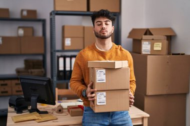 Küçük işletme şirketinde sakallı İspanyol bir adam. Elinde paketlerle kameraya bakıyor. Öpüşme sahnesine bakıyor. aşk ifadesi. 