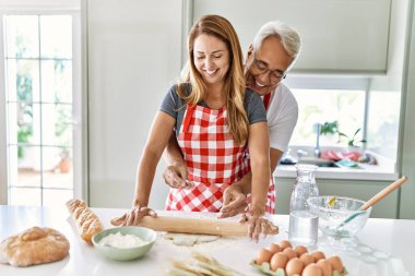 Orta yaşlı İspanyol çift mutlu gülümsüyor ve mutfakta hamur yoğuruyorlar..