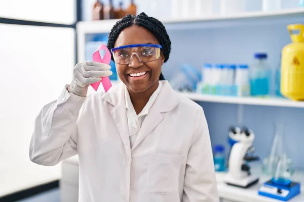 ピンクリボンをつけた科学研究所で働くアフリカ系アメリカ人女性は 前向きな笑顔で立ち上がり 笑顔で歯を見せています — ストック写真