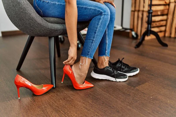 Customer woman choosing high heel shoes at clothing store.