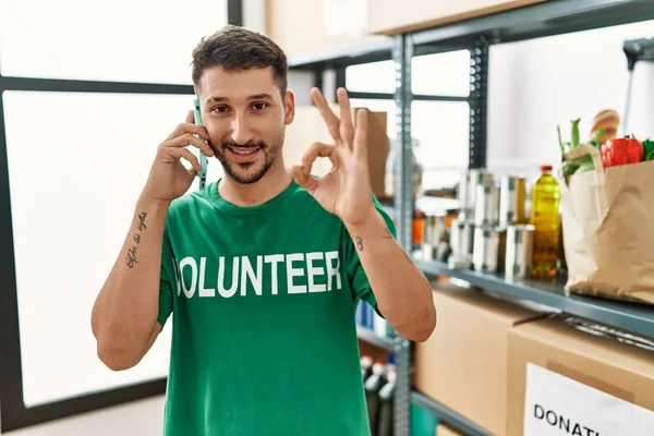 Joven Hombre Hispano Vistiendo Una Camiseta Voluntaria Hablando Por Teléfono — Foto de Stock