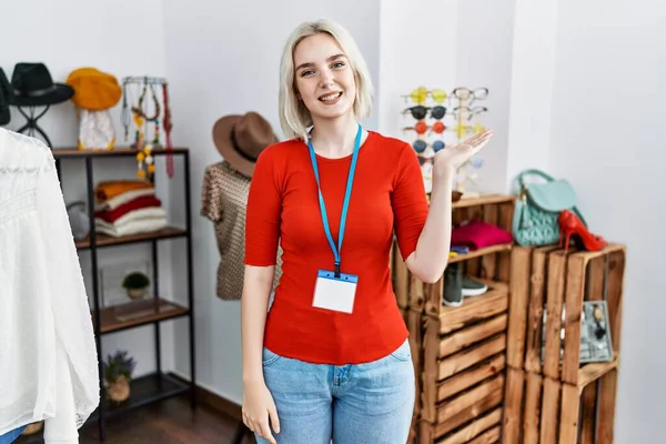 Perakende mağazasında yönetici olarak çalışan genç beyaz kadın neşeli bir şekilde sunum yapıyor ve avuç içi kameraya bakıyor.. 