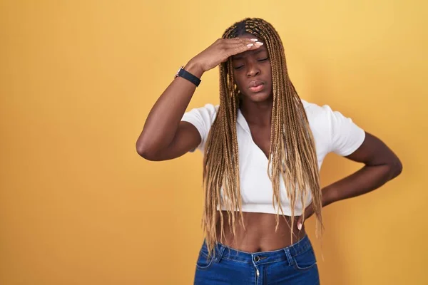 黄色の背景の上に立っている編組の髪を持つアフリカ系アメリカ人女性は心配し 額に手で問題について強調しました 危機への神経と不安 — ストック写真
