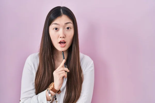 Mujer Joven China Sosteniendo Lápiz Sobre Fondo Rosa Asustado Sorprendido —  Fotos de Stock