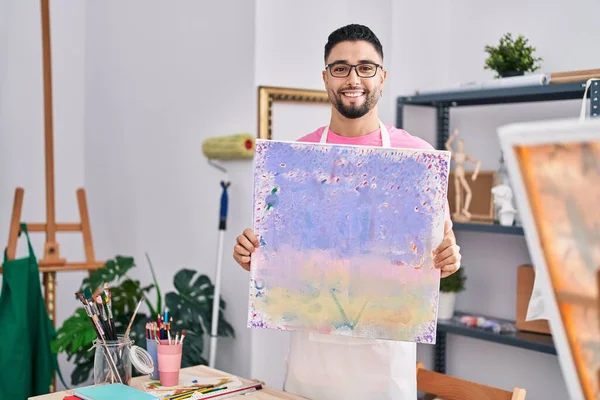 年轻的阿拉伯男子艺术家微笑着自信地在艺术工作室举行画展 — 图库照片