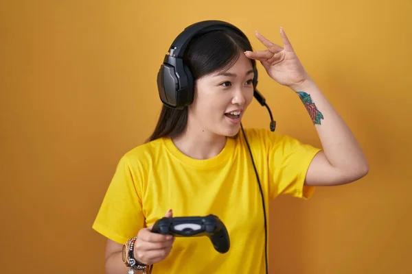 中国的年轻女子玩电子游戏时 手牵着控制器 非常高兴 面带微笑地遥望远方 搜索概念 — 图库照片