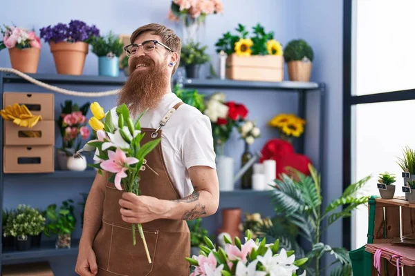 年轻的红头发男人花匠在花店里捧着一束花 — 图库照片