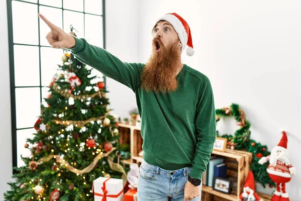 Zrzavý Muž Dlouhými Vousy Vánočním Kloboukem Vánočního Stromku Ukazující Prstem — Stock fotografie