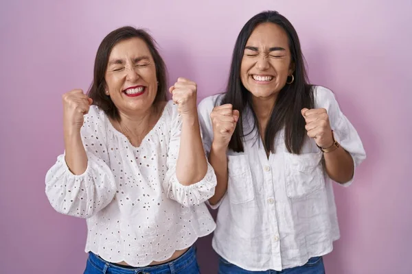 İspanyol anne ve kızı birlikte. Başarının heyecanı içinde kolları havada, gözleri kapalı zaferi kutlarken gülümsüyorlar. Kazanan konsept. 