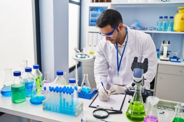 Genç İspanyol bilim adamı laboratuvarda sıvı yazım raporunu ölçüyor.