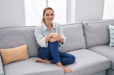 Evdeki koltukta kendinden emin gülümseyen genç bir kadın.