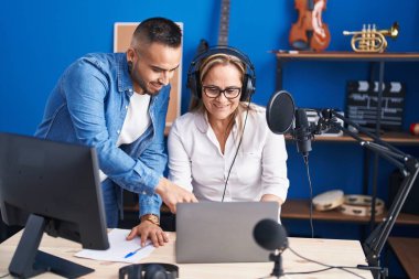 Man and woman musicians listening to music speaking at music studio