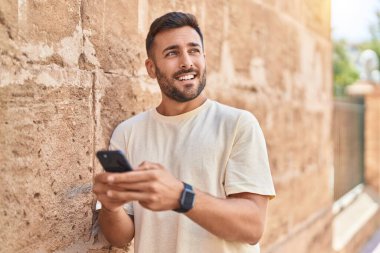 Sokakta akıllı telefon kullanan, kendine güvenen genç bir İspanyol.